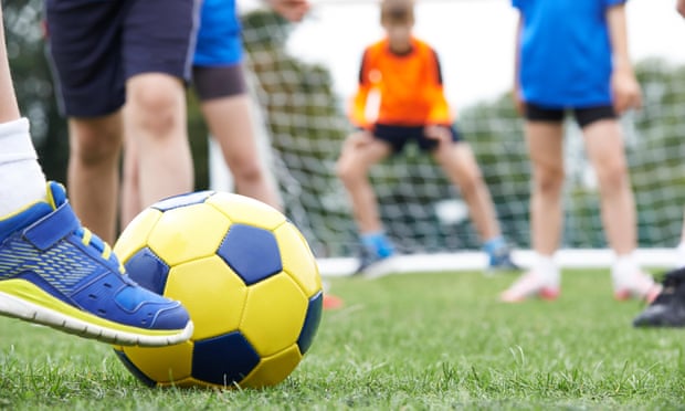 child kicking football