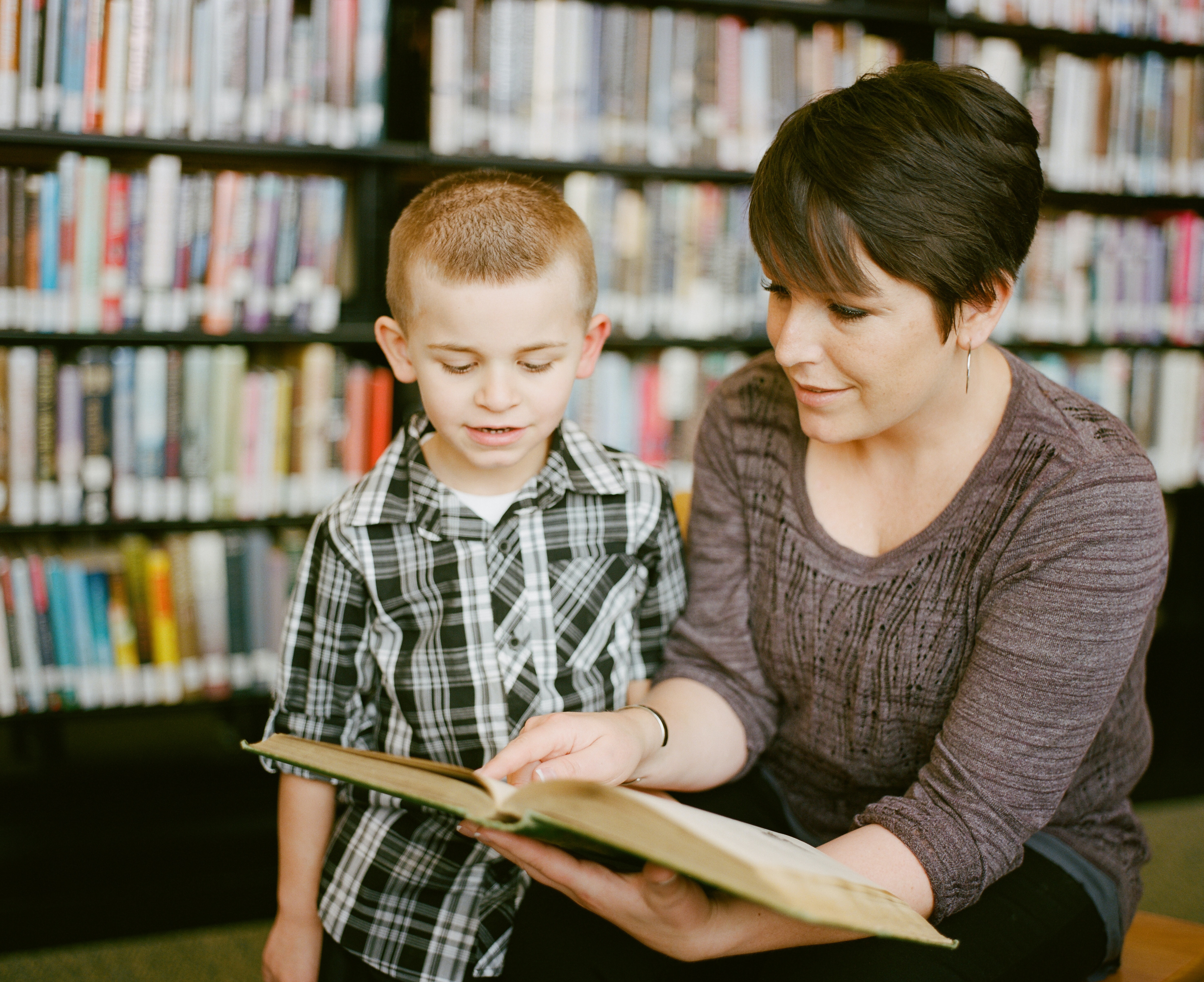 Lady reading a book with a young boy
